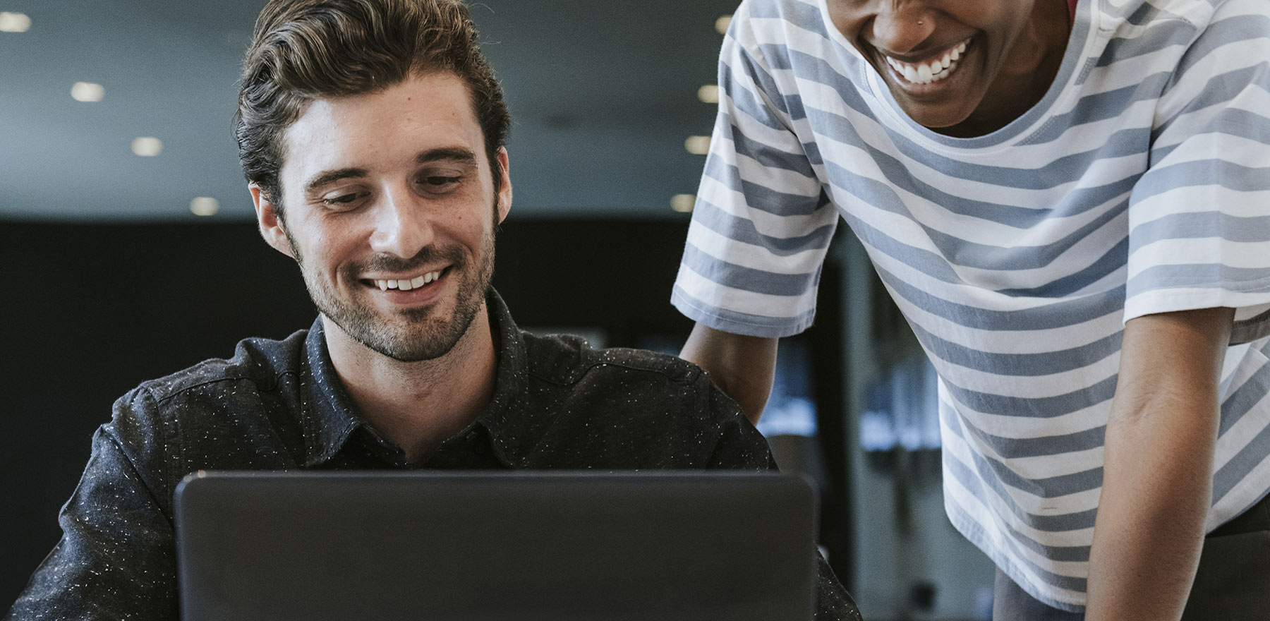 Two men looking at a laptop with a website design on the screen.