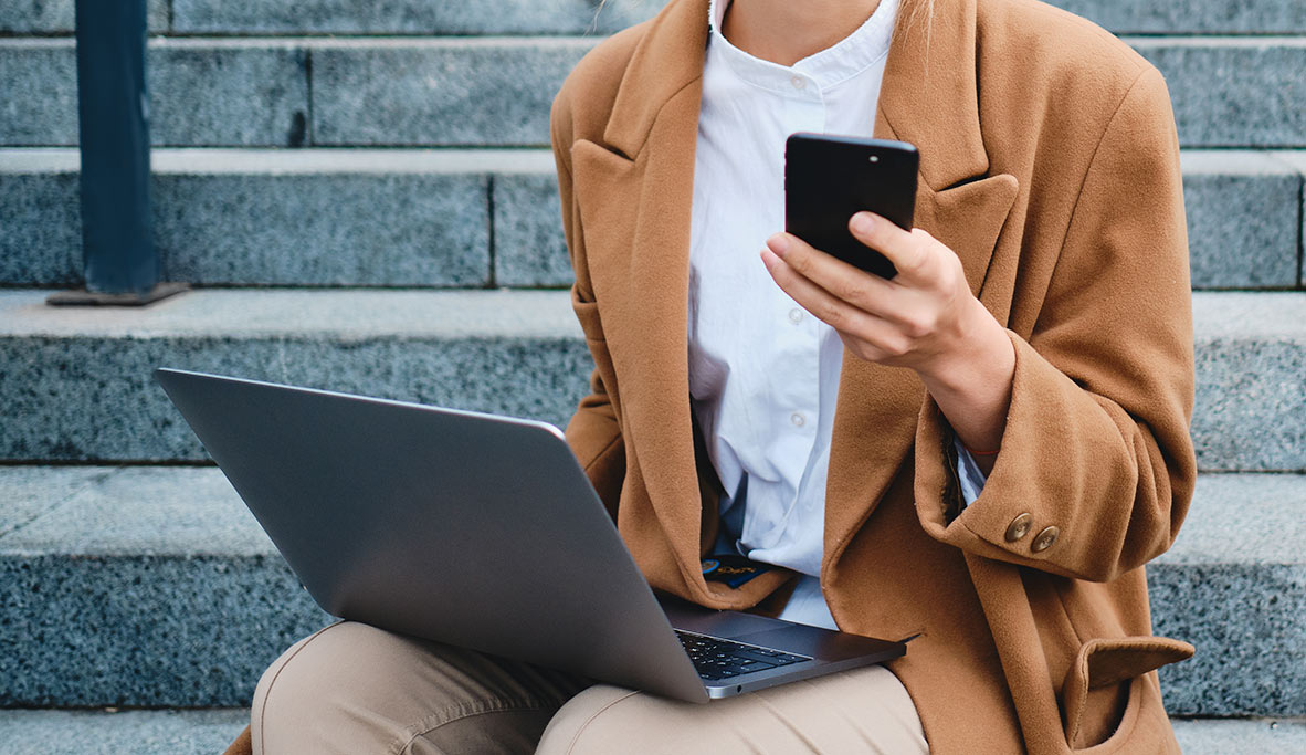 Photo of a women using both a phone and laptop to access website content in Northwest Arkansas.